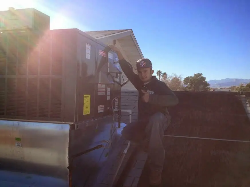 HVAC technician performing AC Tune-Up on a rooftop unit in Avenal